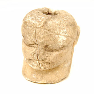 Carved head of bone, pierced through the middle for suspension. Votive offering. 